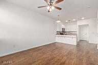 unfurnished living room featuring dark wood-type flooring and a ceiling fan