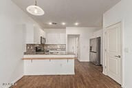 kitchen featuring dark wood finished floors, a peninsula, light countertops, and decorative backsplash