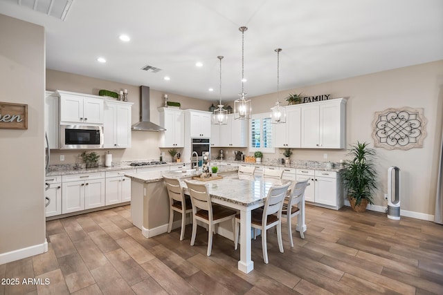 31517 N 41st St, Cave Creek, AZ 85331 - kitchen featuring wall chimney range hood, stainless steel appliances, recessed lighting, wood finished floors, and white cabinets