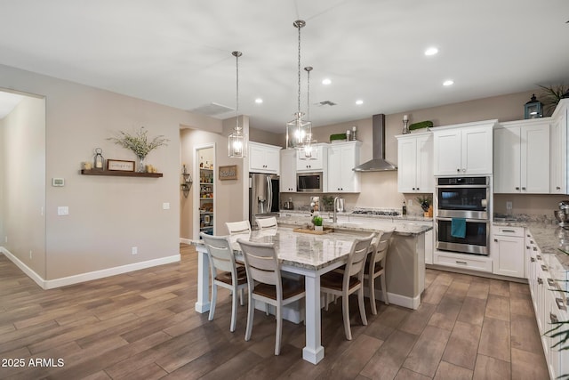 31517 N 41st St, Cave Creek, AZ 85331 - kitchen with wall chimney exhaust hood, appliances with stainless steel finishes, wood finished floors, a center island with sink, and recessed lighting