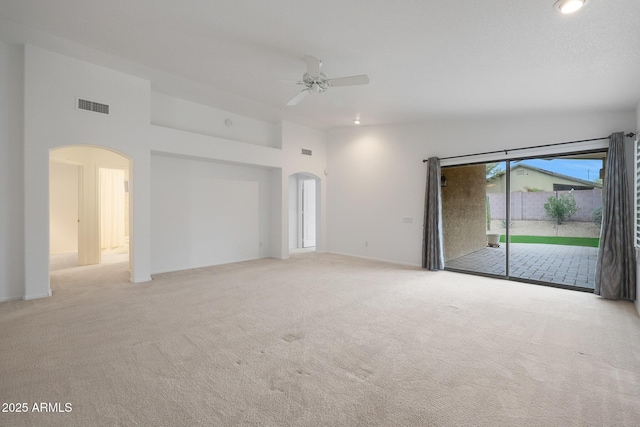 carpeted empty room featuring a towering ceiling and ceiling fan