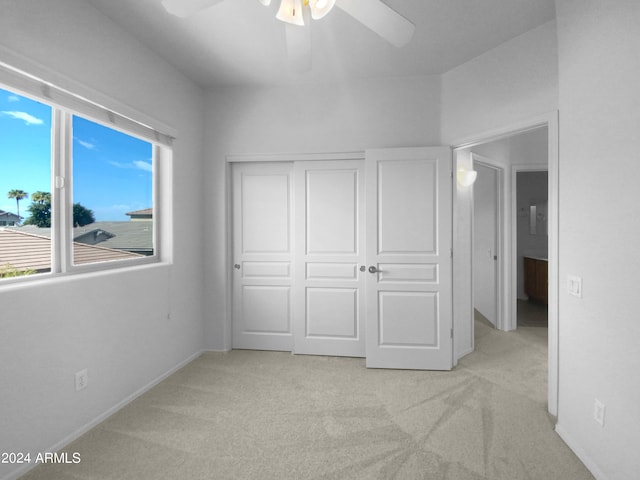 unfurnished bedroom featuring light carpet, ceiling fan, and a closet