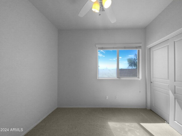 unfurnished bedroom with ceiling fan, a closet, and light colored carpet