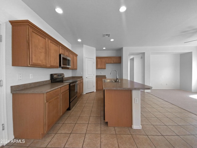 kitchen with light tile patterned flooring, a kitchen island with sink, sink, and range with electric stovetop