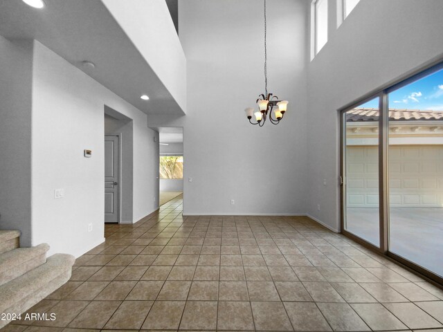 empty room featuring an inviting chandelier, tile patterned floors, and a towering ceiling