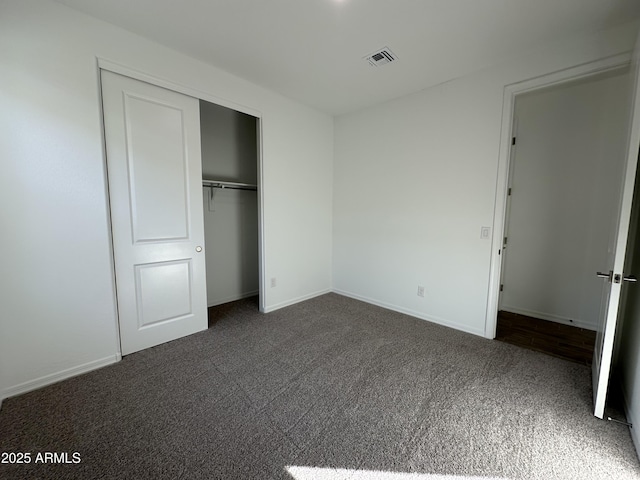 unfurnished bedroom featuring dark carpet and a closet