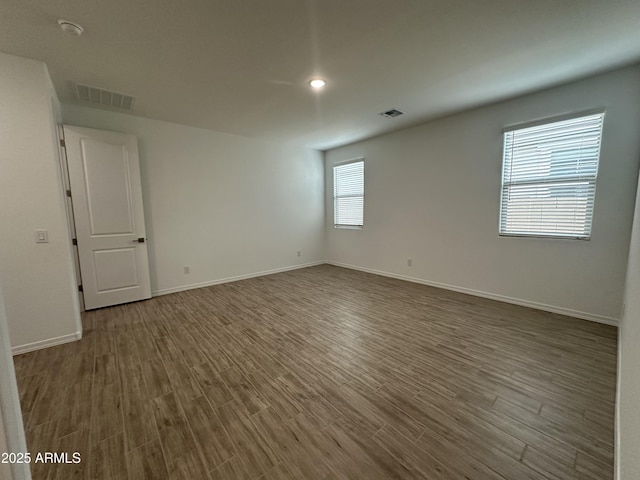 empty room with baseboards, visible vents, and wood finished floors