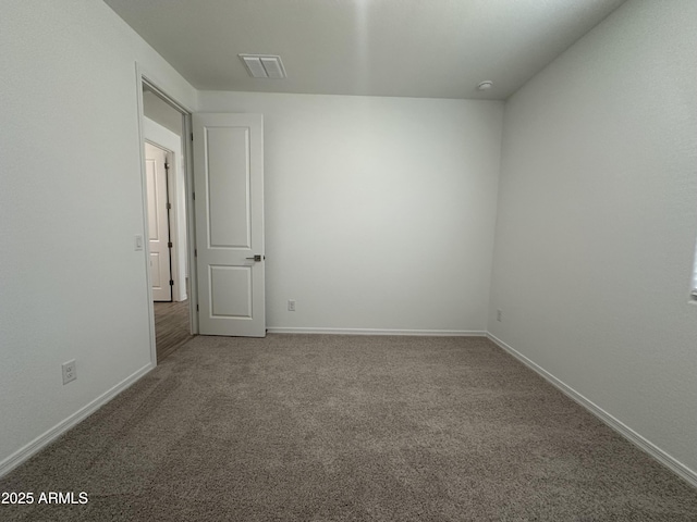 carpeted spare room with visible vents and baseboards