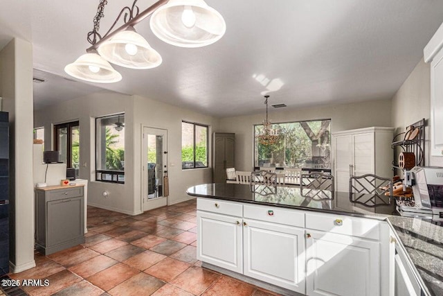 kitchen with dark tile patterned floors, hanging light fixtures, and white cabinetry