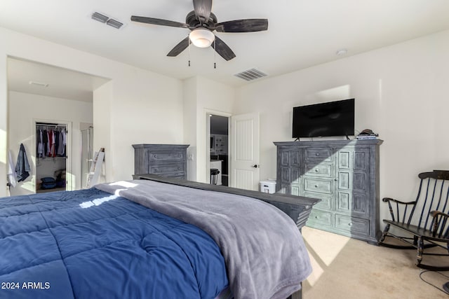 bedroom featuring a spacious closet, light colored carpet, a closet, and ceiling fan