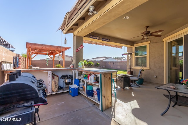 view of patio featuring ceiling fan, exterior bar, and a grill