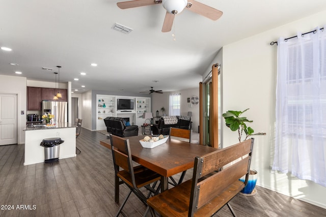 dining area featuring dark hardwood / wood-style floors, built in shelves, a fireplace, and ceiling fan