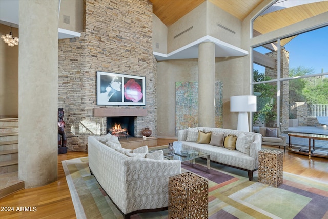 living room featuring high vaulted ceiling, wooden ceiling, a stone fireplace, and wood-type flooring