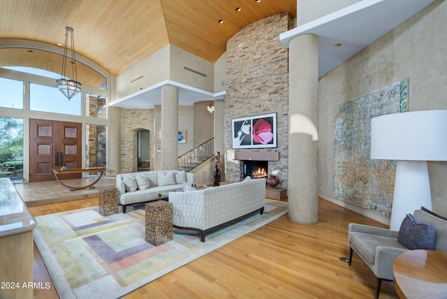 living room featuring high vaulted ceiling, light hardwood / wood-style floors, and a fireplace