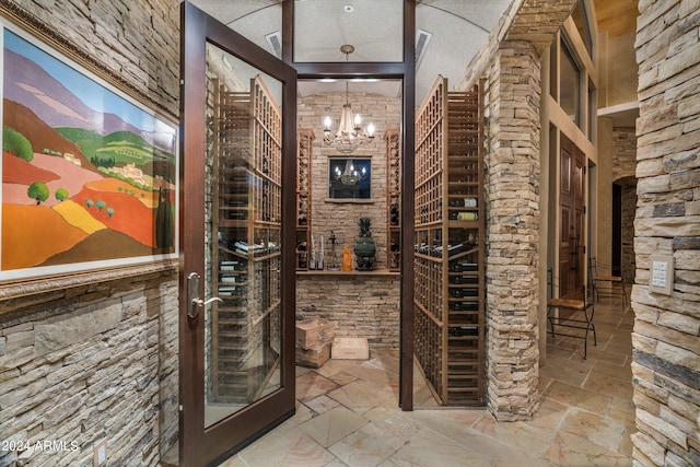 wine room with an inviting chandelier, a textured ceiling, and tile floors