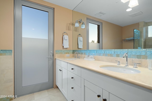 bathroom with tile flooring, double sink, vanity with extensive cabinet space, tile walls, and backsplash