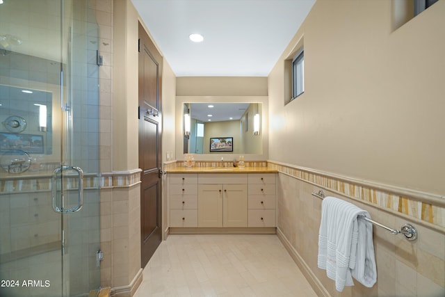 bathroom featuring a shower with door, tile flooring, and vanity