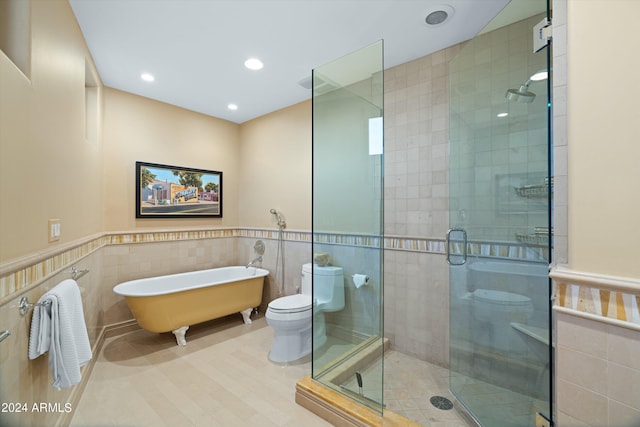 bathroom featuring separate shower and tub, toilet, and tile walls