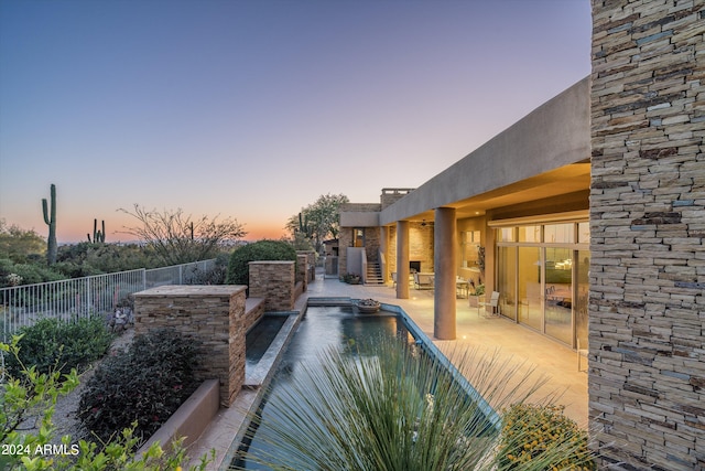 pool at dusk featuring a patio area