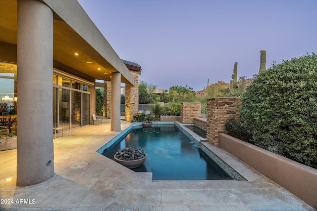 pool at dusk featuring a patio area