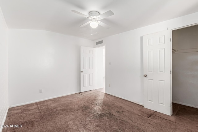 unfurnished bedroom featuring carpet flooring, ceiling fan, a walk in closet, and a closet