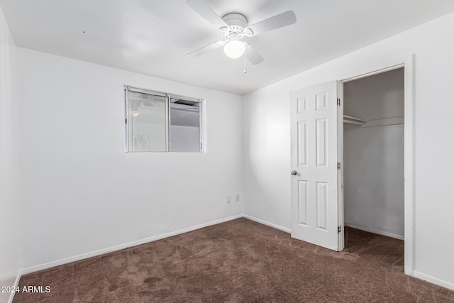 unfurnished bedroom featuring ceiling fan, dark carpet, and a closet