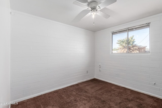 carpeted empty room featuring ceiling fan and brick wall