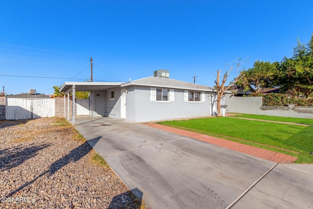 ranch-style house with concrete driveway, an attached carport, a front yard, and fence