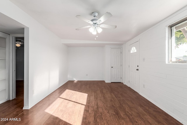 interior space featuring ceiling fan, dark hardwood / wood-style flooring, and brick wall