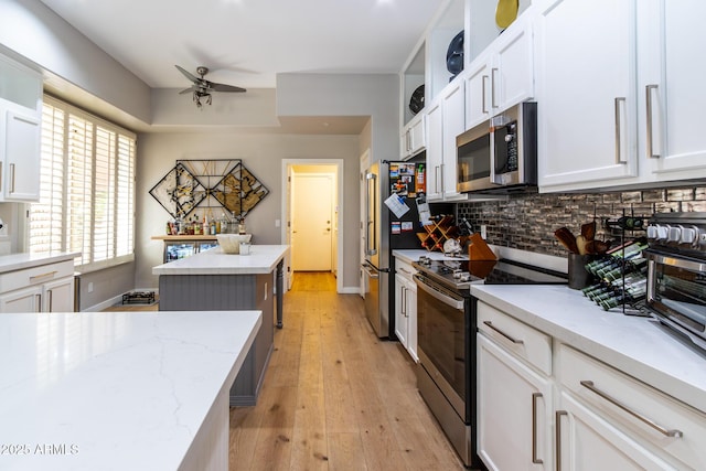 kitchen with light stone countertops, stainless steel appliances, a kitchen island, and white cabinetry