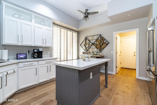 kitchen with light hardwood / wood-style flooring, white cabinetry, high quality fridge, and a kitchen island