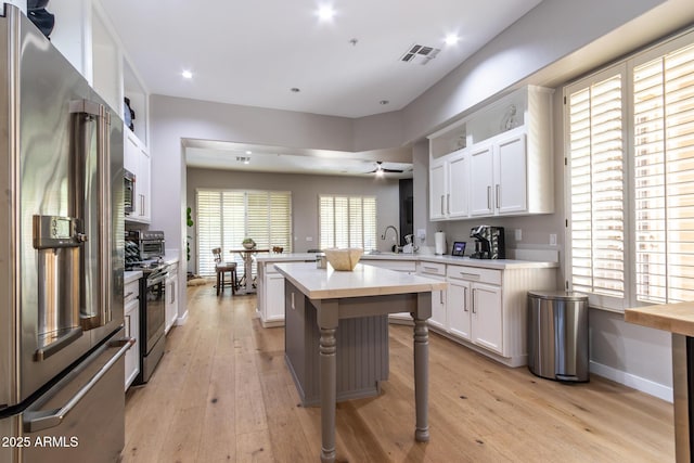 kitchen featuring a kitchen bar, stainless steel appliances, white cabinetry, and a kitchen island