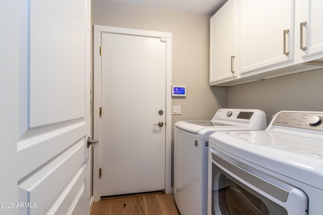 laundry room featuring washer and dryer, light wood-type flooring, and cabinets