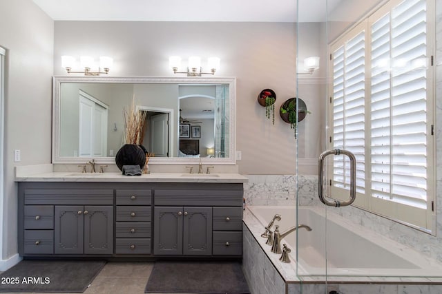 bathroom featuring tile patterned flooring, vanity, and a relaxing tiled tub