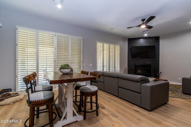 living room with a fireplace, light wood-type flooring, and ceiling fan