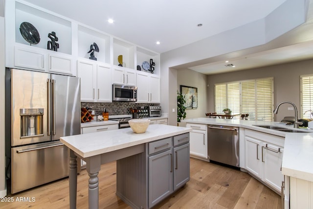 kitchen with a center island, sink, stainless steel appliances, light stone counters, and white cabinets