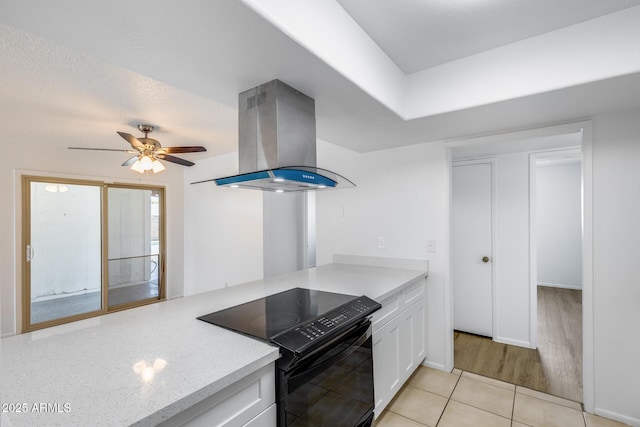 5504 N 69th Ave, Glendale, AZ 85303 - kitchen with electric range, island range hood, white cabinets, light tile patterned floors, and a ceiling fan