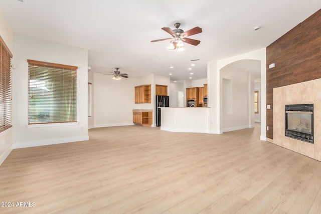 unfurnished living room featuring a fireplace, ceiling fan, and light hardwood / wood-style flooring