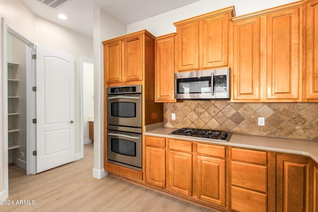 kitchen with decorative backsplash, light wood-type flooring, and stainless steel appliances