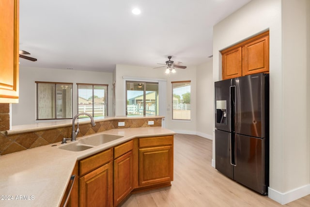 kitchen featuring a healthy amount of sunlight, sink, stainless steel refrigerator with ice dispenser, and light hardwood / wood-style flooring