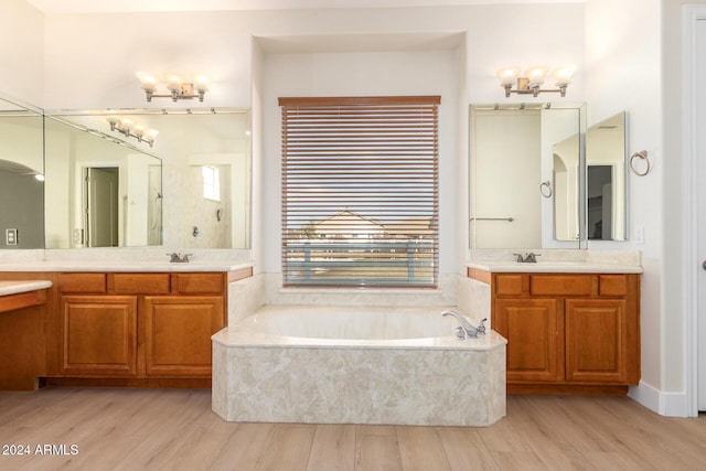 bathroom with tiled tub, hardwood / wood-style floors, and vanity