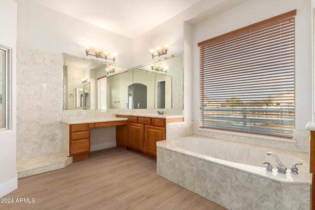 bathroom with hardwood / wood-style floors, vanity, and tiled tub