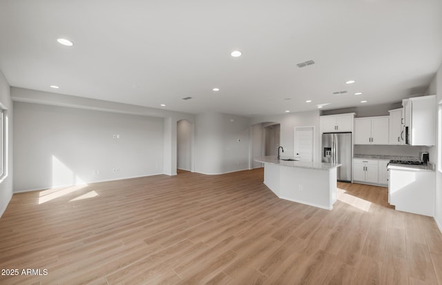 kitchen with stainless steel appliances, visible vents, open floor plan, a kitchen island with sink, and a sink