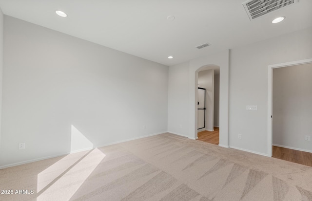 spare room featuring arched walkways, visible vents, baseboards, and recessed lighting