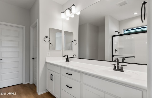 bathroom featuring double vanity, wood finished floors, a sink, and visible vents