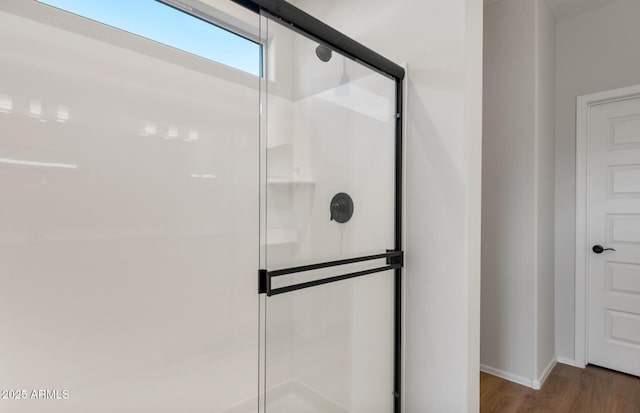 bathroom with a stall shower, baseboards, and wood finished floors