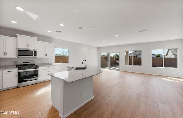 kitchen with white cabinetry, a kitchen island with sink, visible vents, and stainless steel appliances