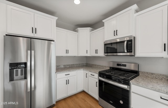 kitchen with light wood-type flooring, white cabinetry, stainless steel appliances, and light stone counters