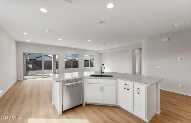 kitchen featuring stainless steel dishwasher, an island with sink, a sink, and white cabinetry