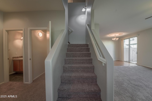 stairway with carpet floors and a chandelier